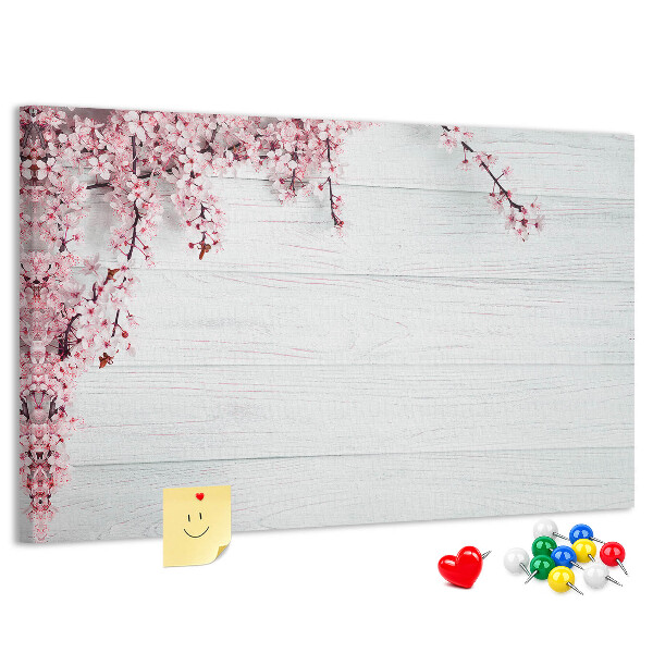 Tablero de corcho decorado con diseño de ramas florales sobre fondo de madera blanca