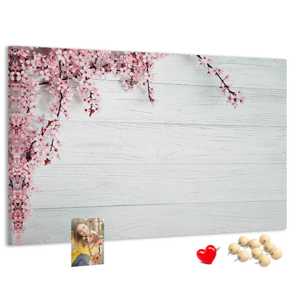 Tablero de corcho decorado con diseño de ramas florales sobre fondo de madera blanca