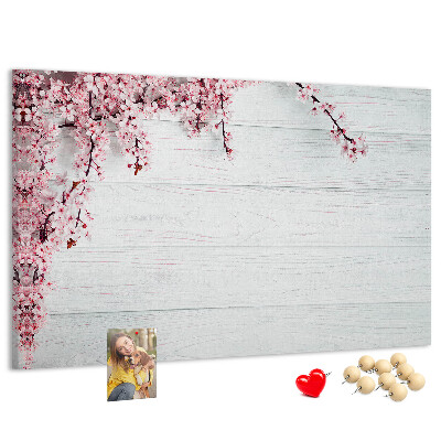 Tablero de corcho decorado con diseño de ramas florales sobre fondo de madera blanca