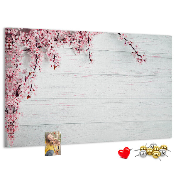 Tablero de corcho decorado con diseño de ramas florales sobre fondo de madera blanca