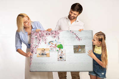 Tablero de corcho decorado con diseño de ramas florales sobre fondo de madera blanca