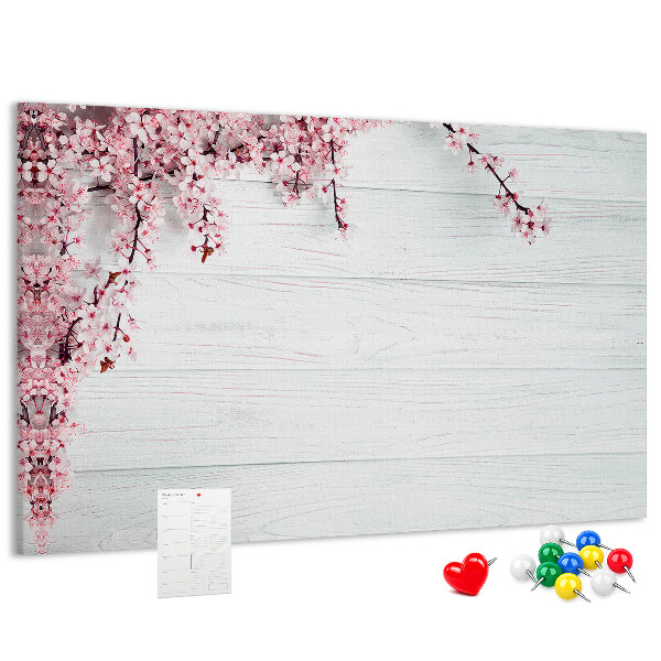 Tablero de corcho decorado con diseño de ramas florales sobre fondo de madera blanca