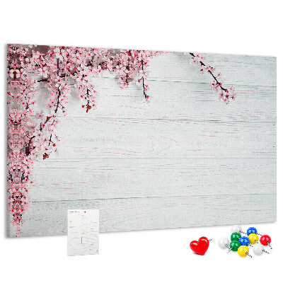 Tablero de corcho decorado con diseño de ramas florales sobre fondo de madera blanca