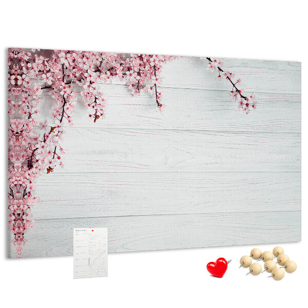 Tablero de corcho decorado con diseño de ramas florales sobre fondo de madera blanca