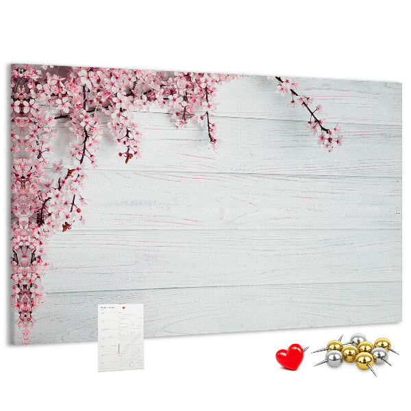 Tablero de corcho decorado con diseño de ramas florales sobre fondo de madera blanca