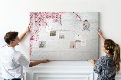 Tablero de corcho decorado con diseño de ramas florales sobre fondo de madera blanca