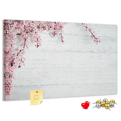 Tablero de corcho decorado con diseño de ramas florales sobre fondo de madera blanca