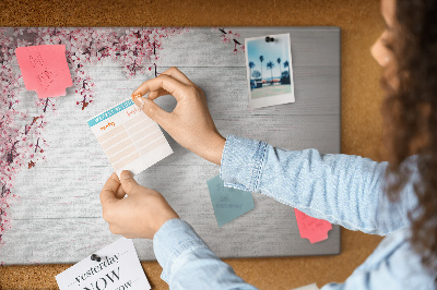 Tablero de corcho decorado con diseño de ramas florales sobre fondo de madera blanca
