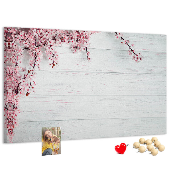 Tablero de corcho decorado con diseño de ramas florales sobre fondo de madera blanca