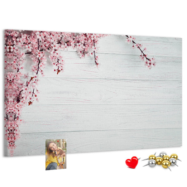 Tablero de corcho decorado con diseño de ramas florales sobre fondo de madera blanca