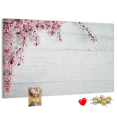 Tablero de corcho decorado con diseño de ramas florales sobre fondo de madera blanca