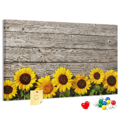 Tablero de corcho decorado Girasoles sobre un fondo de tablas de madera.