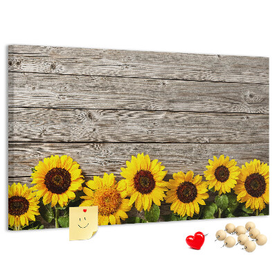 Tablero de corcho decorado con diseño de girasoles sobre fondo de tablas de madera