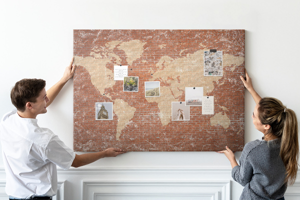 Tablero de corcho decorado Un mapamundi contra una pared de ladrillos
