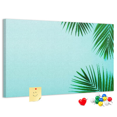 Tablero de corcho decorado con diseño de hojas tropicales sobre fondo azul