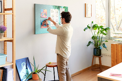 Tablero de corcho decorado con diseño de hojas tropicales sobre fondo azul