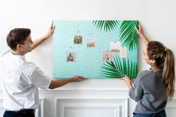 Tablero de corcho decorado con diseño de hojas tropicales sobre fondo azul