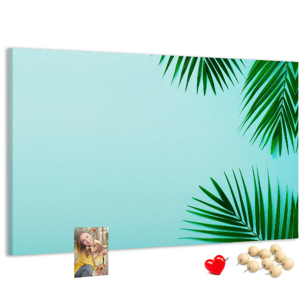 Tablero de corcho decorado con diseño de hojas tropicales sobre fondo azul