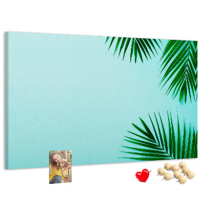 Tablero de corcho decorado con diseño de hojas tropicales sobre fondo azul