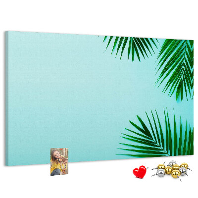 Tablero de corcho decorado con diseño de hojas tropicales sobre fondo azul