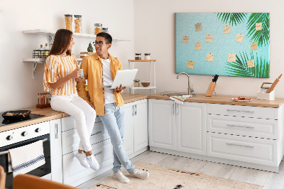 Tablero de corcho decorado con diseño de hojas tropicales sobre fondo azul