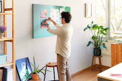 Tablero de corcho decorado con diseño de hojas tropicales sobre fondo azul