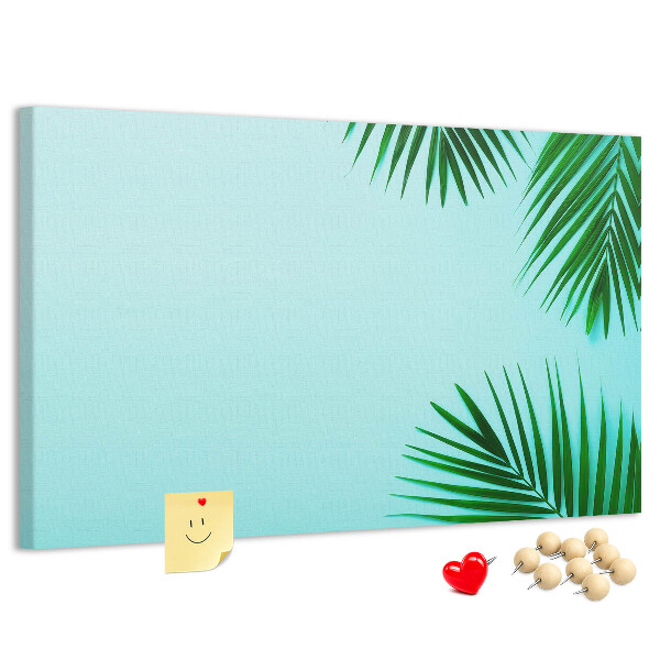 Tablero de corcho decorado con diseño de hojas tropicales sobre fondo azul