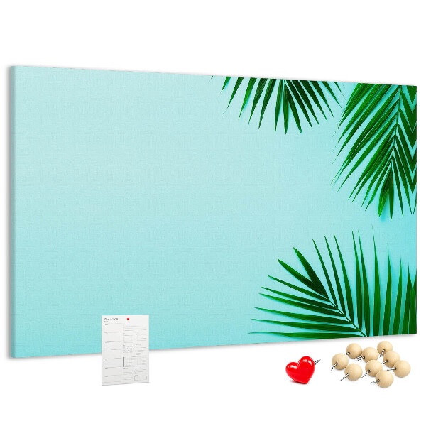 Tablero de corcho decorado con diseño de hojas tropicales sobre fondo azul