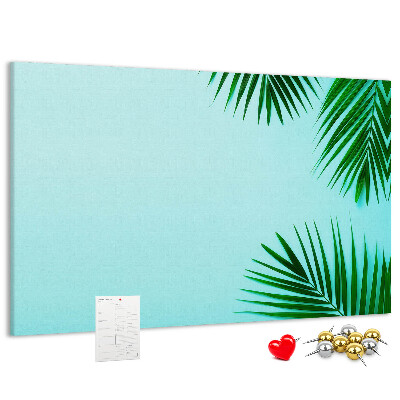 Tablero de corcho decorado con diseño de hojas tropicales sobre fondo azul
