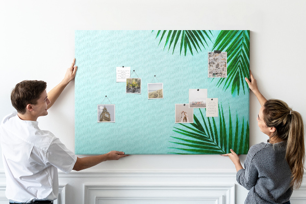 Tablero de corcho decorado con diseño de hojas tropicales sobre fondo azul