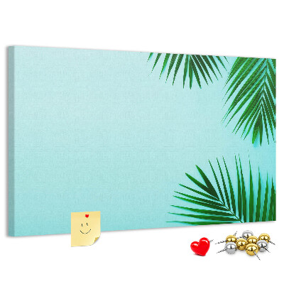 Tablero de corcho decorado con diseño de hojas tropicales sobre fondo azul