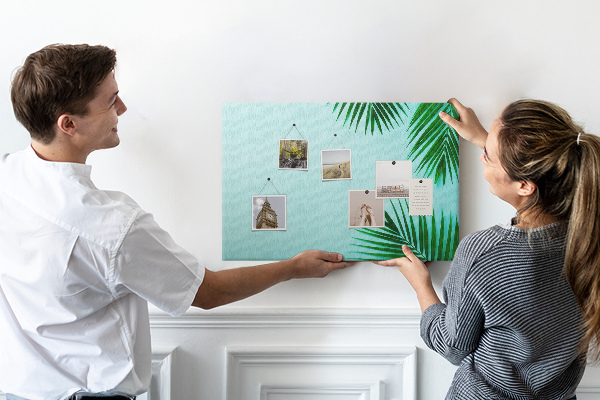 Tablero de corcho decorado con diseño de hojas tropicales sobre fondo azul