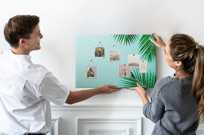 Tablero de corcho decorado con diseño de hojas tropicales sobre fondo azul