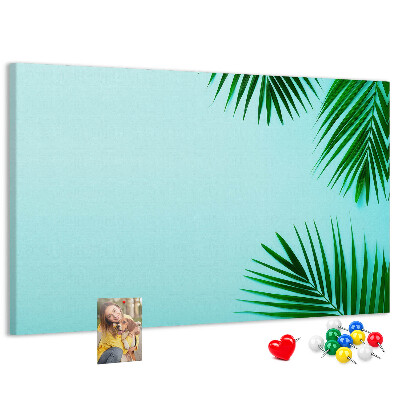 Tablero de corcho decorado con diseño de hojas tropicales sobre fondo azul