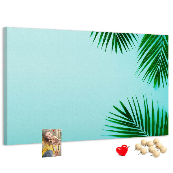Tablero de corcho decorado con diseño de hojas tropicales sobre fondo azul