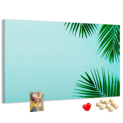 Tablero de corcho decorado con diseño de hojas tropicales sobre fondo azul
