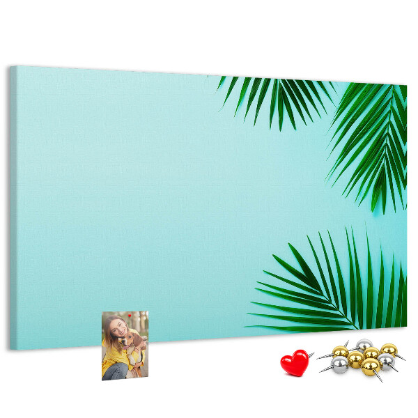 Tablero de corcho decorado con diseño de hojas tropicales sobre fondo azul