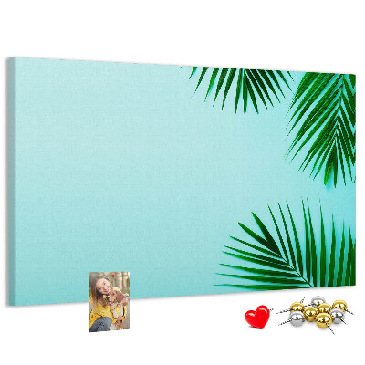 Tablero de corcho decorado con diseño de hojas tropicales sobre fondo azul