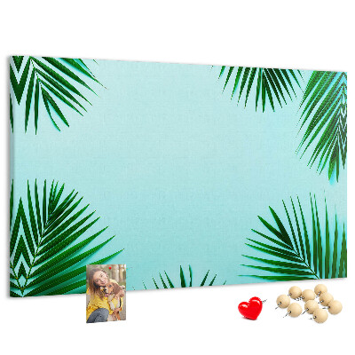 Pizarra de corcho con diseño de hojas tropicales sobre fondo azul