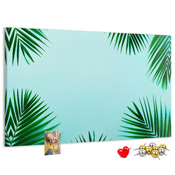Pizarra de corcho con diseño de hojas tropicales sobre fondo azul