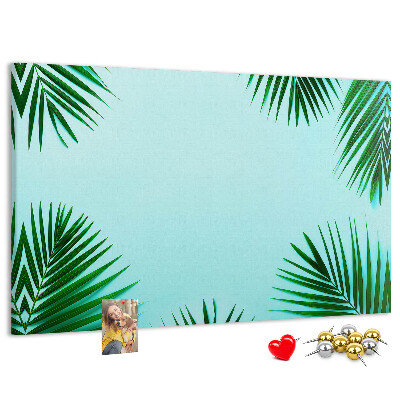 Pizarra de corcho con diseño de hojas tropicales sobre fondo azul
