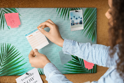 Pizarra de corcho con diseño de hojas tropicales sobre fondo azul
