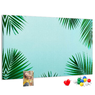 Pizarra de corcho con diseño de hojas tropicales sobre fondo azul