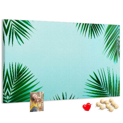 Pizarra de corcho con diseño de hojas tropicales sobre fondo azul