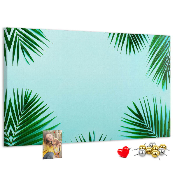 Pizarra de corcho con diseño de hojas tropicales sobre fondo azul