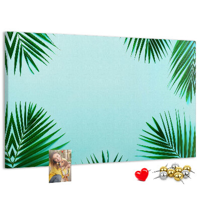 Pizarra de corcho con diseño de hojas tropicales sobre fondo azul