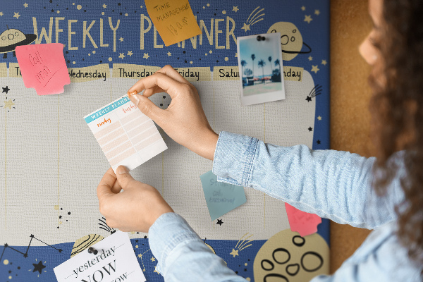 Tablero de corcho decorado planificador semanal con diseño de planetas y estrellas