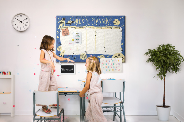 Tablero de corcho decorado planificador semanal con diseño de planetas y estrellas