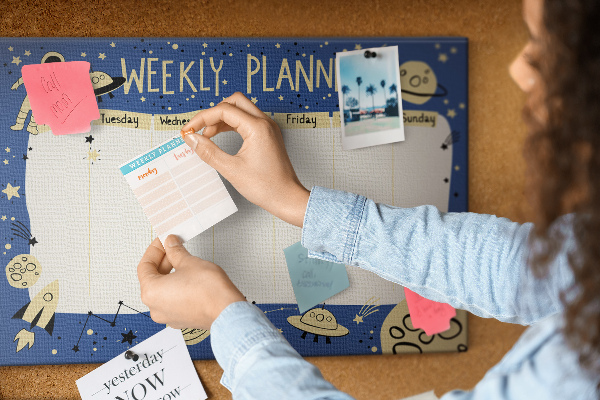 Tablero de corcho decorado planificador semanal con diseño de planetas y estrellas