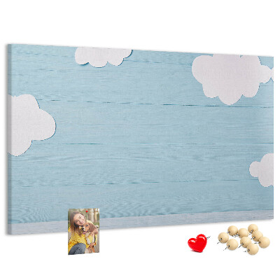 Pizarra de corcho con diseño de cielo con nubes sobre fondo de madera